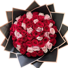 Bouquet of red and pale pink roses wrapped in black paper