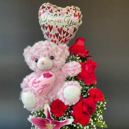 Pink teddy bear with heart balloon and red roses in a white basket