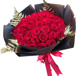 Bouquet of red roses wrapped in black paper with a pink ribbon