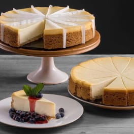 Three cheesecake desserts on plates and a cake stand