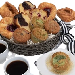 Basket of assorted pastries and muffins with cups of coffee