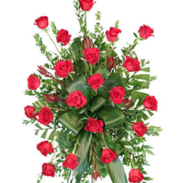Standing spray of red roses with greenery on an easel