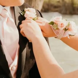 Pink rose boutonnieres being pinned to a suit jacket