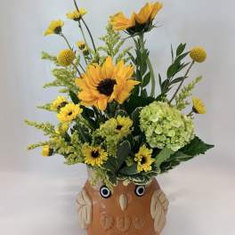 Sunflower and yellow flower arrangement in an owl-shaped ceramic pot