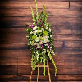 Tall floral standing spray with white, green, and purple blooms on an easel