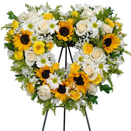 Heart-shaped floral wreath with sunflowers, white roses, and daisies on an easel