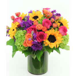 Bouquet of sunflowers, pink roses, orange spray roses, and purple flowers in a glass vase