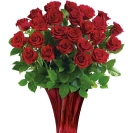 Red roses arranged in a tall red glass vase