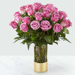 Pink roses arranged in a clear glass vase with a gold base