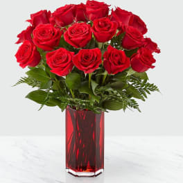 Red roses arranged in a tall red glass vase