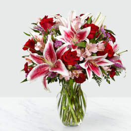 Bouquet of pink lilies and red roses in a clear glass vase