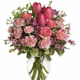Pink tulips and roses arranged in a clear glass vase