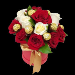 Red and white roses with gold-wrapped chocolates in a pink box