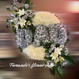 Oval funeral spray reading DAD in silver roses on white mums with white lilies and black accents.