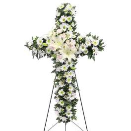White floral cross on a stand with lilies and daisies