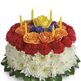 Tiered floral cake with red, orange, and white flowers and yellow candles