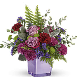 Purple roses and magenta mums in a lavender glass vase