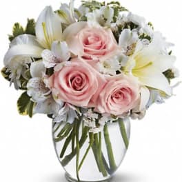 Pink roses and white lilies arranged in a clear glass vase
