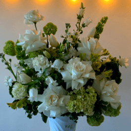White floral arrangement in a white vase with green accents