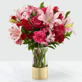 Pink lilies and red roses arranged in a clear glass vase