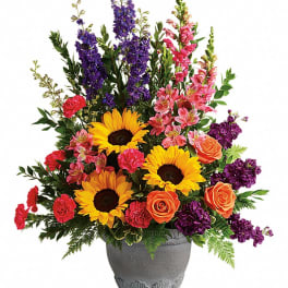 Colorful bouquet with sunflowers, roses, and purple spikes in a gray vase