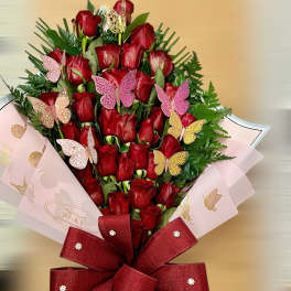 Tall bouquet of red roses with pink butterflies and a large red bow in pink wrap