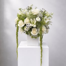 White floral arrangement with roses and lilies in a white vase