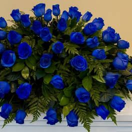 Large spray of vivid blue roses arranged in a low mound on a white surface