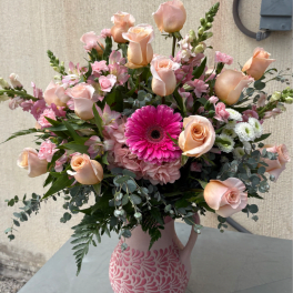 Pink and peach flower arrangement in a patterned vase