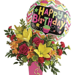 Bright birthday arrangement with yellow lilies, pink roses, orange flowers and a Happy Birthday balloon in a pink vase