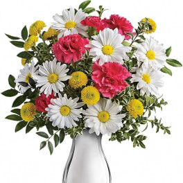White daisies, yellow button poms, and pink carnations arranged in a sleek white vase
