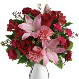Pink lilies, roses, and carnations arranged in a sleek silver vase