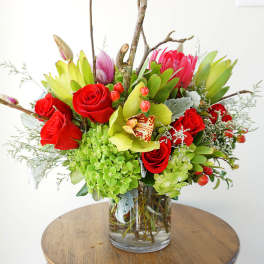 Bouquet of red roses and green blooms in a clear glass vase