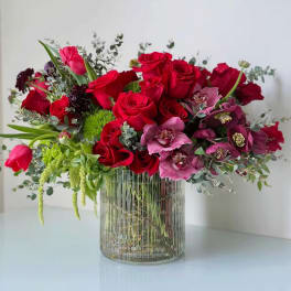 Red roses and pink orchids in a clear ribbed glass vase