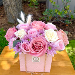 Pink and white roses with lavender blooms in a pink gift box