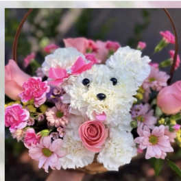 Pink and white flower arrangement shaped like a teddy bear in a basket