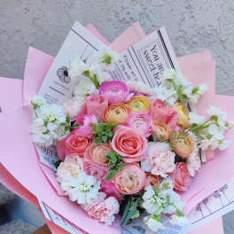 Pink and white bouquet with roses and ranunculus wrapped in pastel paper