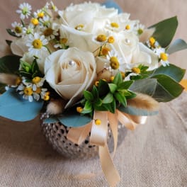 White rose bouquet with small daisy-like flowers and a ribbon-tied vase