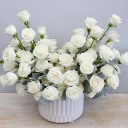 White rose arrangement in a ribbed white vase