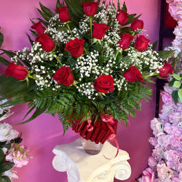Red roses arranged in a clear vase with white baby's breath