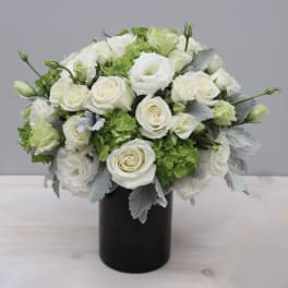 White rose bouquet in a black vase with green accents