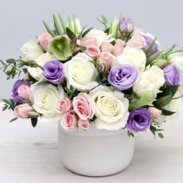 Bouquet of white, pink, and purple roses in a white vase