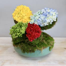 Colorful floral arrangement in a turquoise bowl with moss-covered sections