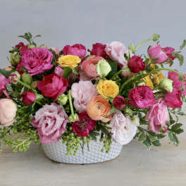 Mixed pink and yellow flower arrangement in a white vase
