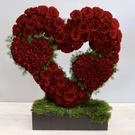 Heart-shaped arrangement of red roses on a moss-covered base