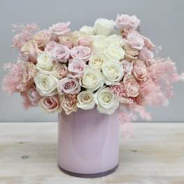 Pink and white roses arranged in a pastel pink vase