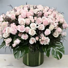 Large bouquet of pale pink and white roses in a green glass vase