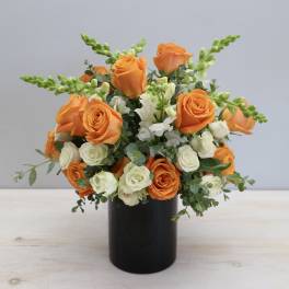 Orange and white roses in a black vase