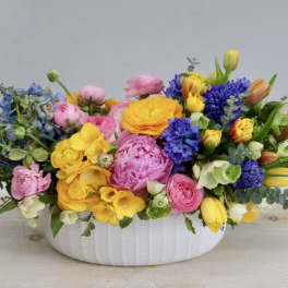 Colorful mixed flower arrangement in a white oval vase