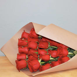 Bouquet of red roses wrapped in tan paper with a red ribbon